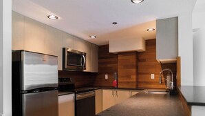 Una cocina moderna con electrodomésticos de acero inoxidable, paneles de madera y luces empotradas en el techo.
