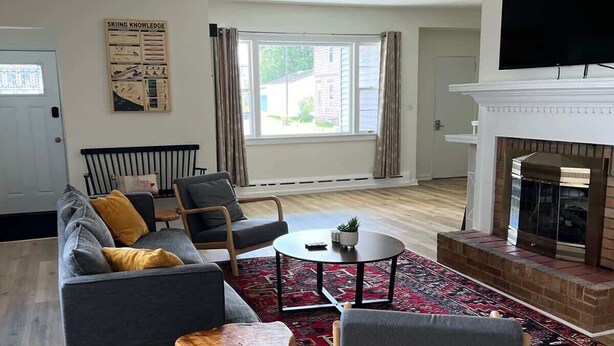 Una sala de estar con sofá, sillas, una mesa de centro, chimenea y televisor.