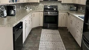 Una cocina con armarios blancos, microondas, estufa y tostadora.