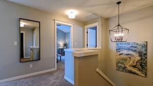 A hallway with a large mirror, a ceiling light, and a wall-mounted artwork.