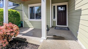 A house with a covered porch, a dark front door, and a small garden with pink flowers.