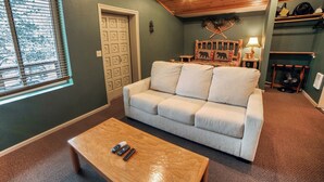 Ein Wohnzimmer mit beiger Couch, einem Holztisch und einem Kamin.