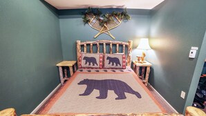 Ein Bett mit einer Bettdecke mit Bärenmotiv, einem Holz-Kopfteil und Nachttischen.