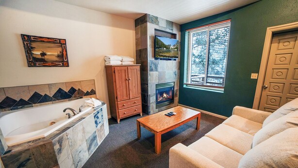 Ein Badezimmer mit Badewanne, Holzschrank, Kamin und einem Fenster mit Jalousien.