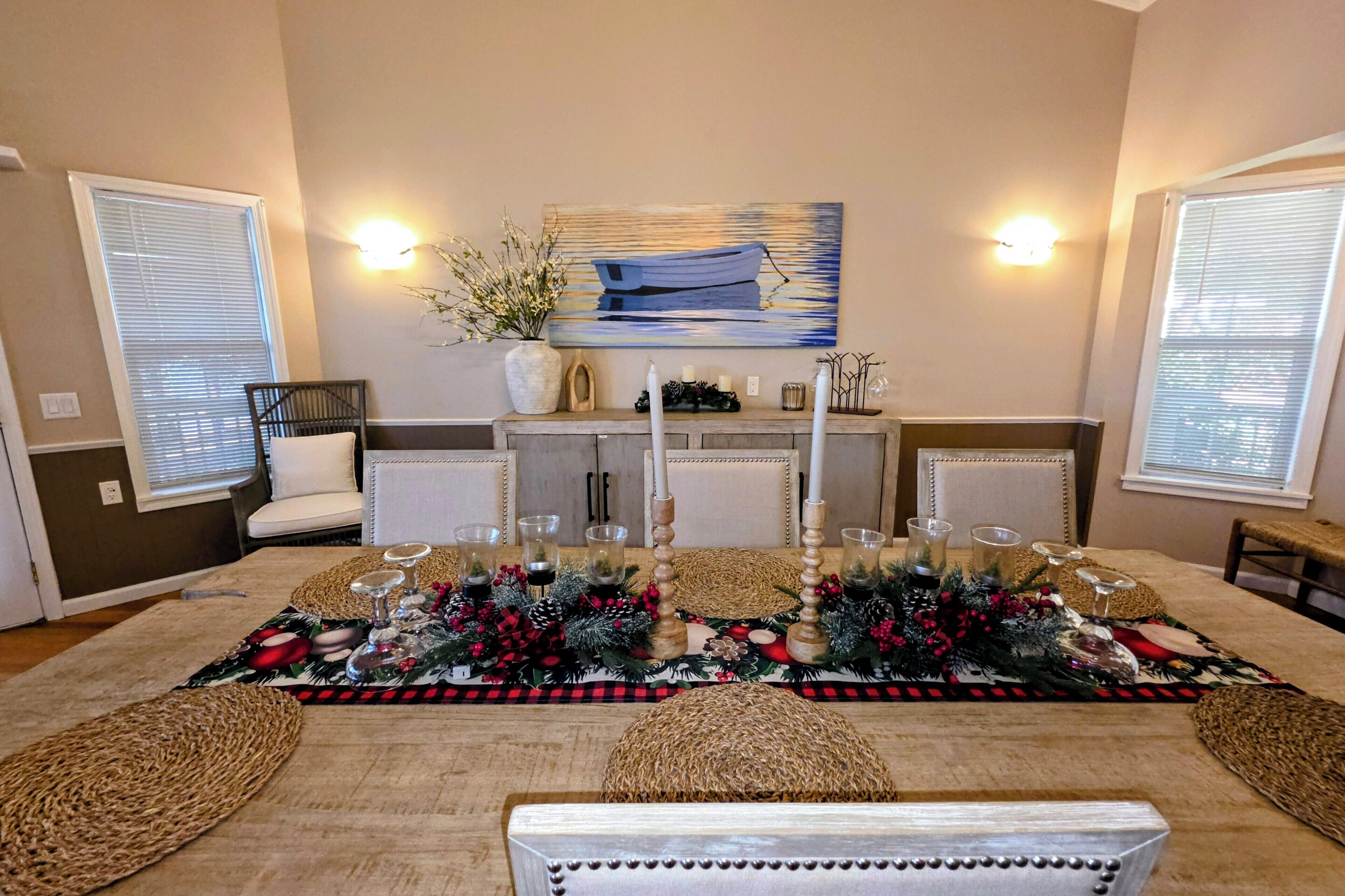 Un coin repas avec une table dressée pour six personnes, agrémenté d’un chemin de table festif, de bougies et de beaux verres.