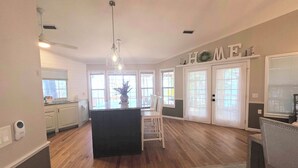 Cocina amplia con una isla central, muebles blancos y un ventilador de techo.