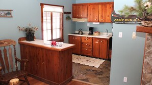Una cocina con armarios de madera, una cafetera y un cartel que dice 'Camp Run-A-M'.