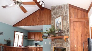 Una cocina rústica con armarios de madera, chimenea de piedra y ventilador de techo.