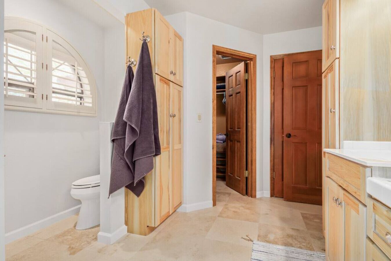 A bathroom with a toilet, wooden cabinets, and a towel rack.