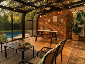 A covered patio area with a brick wall, a pool, and outdoor furniture.