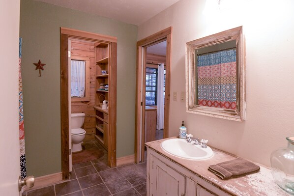 Un baño con tocador de madera, lavamanos y espejo.