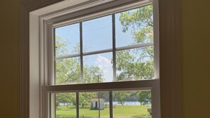 A room with a large window overlooking a grassy area and a small building. - Coffee Creek Cottage: A tranquil, waterfront escape minutes from Oriental, NC (Merritt)