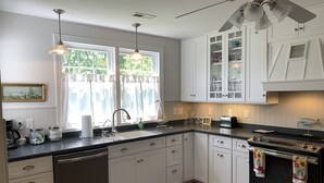 A modern kitchen with white cabinetry, a dishwasher, a stove, and a ceiling fan. - Coffee Creek Cottage: A tranquil, waterfront escape minutes from Oriental, NC (Merritt)