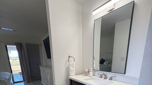 A bathroom with a white marble floor, a large mirror, and a white vanity with drawers. - 2/2 Duplex on CANAL all updated; new furniture, (Rotonda West)