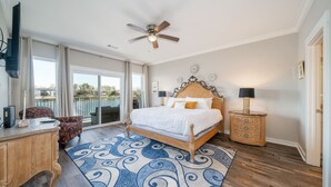 A bedroom with a large bed, a ceiling fan, a desk, a chair, and a view of the outdoors. - The Lookout - Lake Views, Swim, Fish, & More! (Hot Springs)