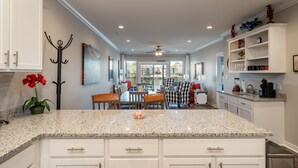 A modern kitchen with white cabinets, granite countertops, and a dining area with a checkered tablecloth. - The Lookout - Lake Views, Swim, Fish, & More! (Hot Springs)
