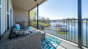 A balcony with wicker furniture, a ceiling fan, and a view of a lake with boats. - The Lookout - Lake Views, Swim, Fish, & More! (Hot Springs)