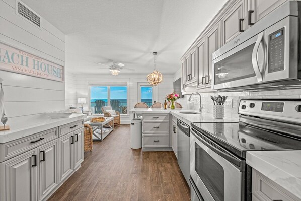 A modern kitchen with white cabinetry, a large island, and a view of the ocean. - Specials ~ A Beach Dream 5 ~ BeachFront ~ Yes, That'S Your View! ~ (Bradenton Beach)