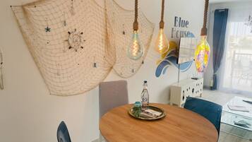 Een eetgedeelte met een ronde houten tafel, gestreepte stoelen en decoratief net aan de muur.