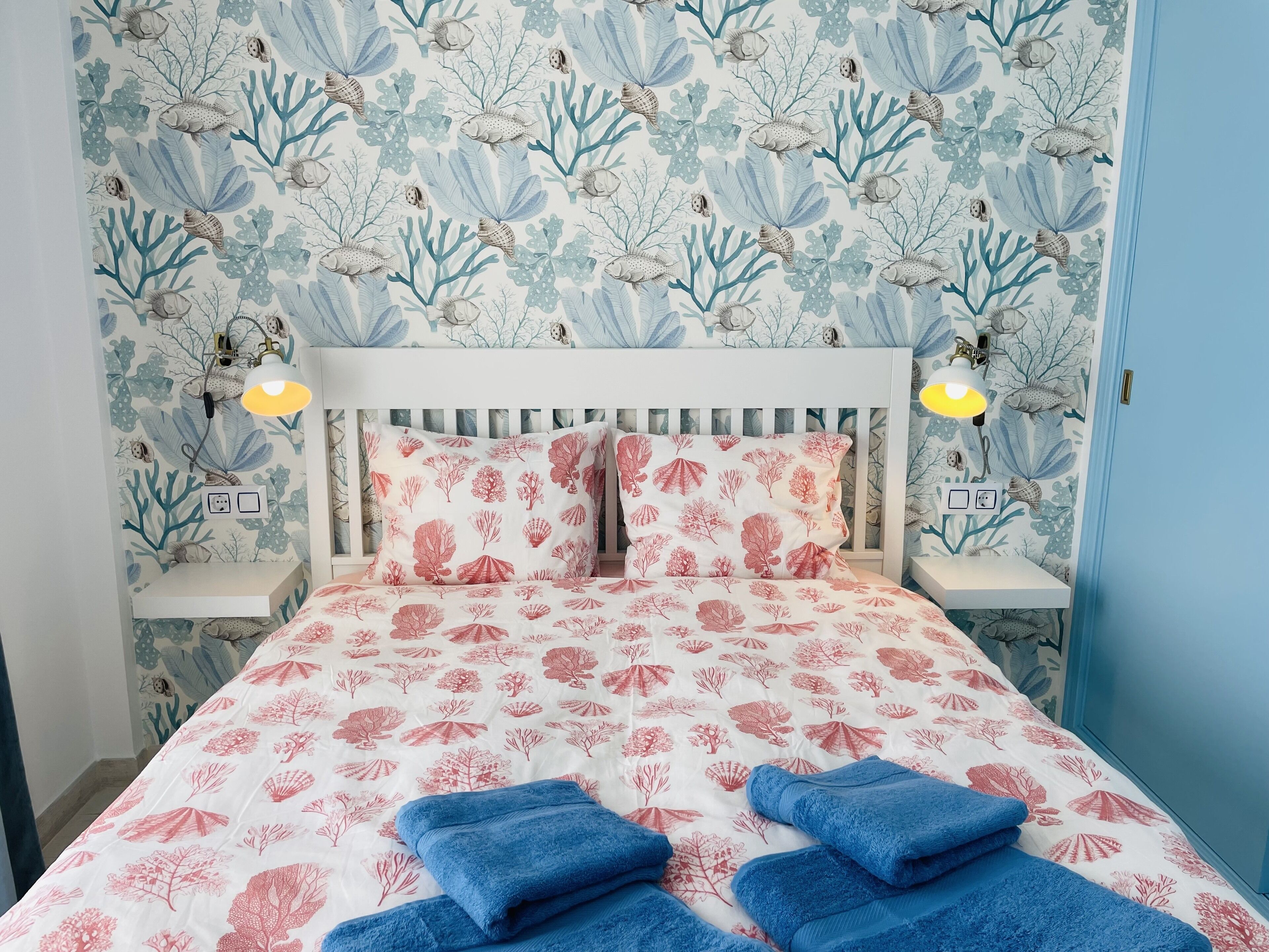 Een slaapkamer met een bed, twee nachtkastjes en een bijzettafeltje.