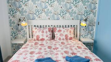 Een slaapkamer met een bed, twee nachtkastjes en een bijzettafeltje.