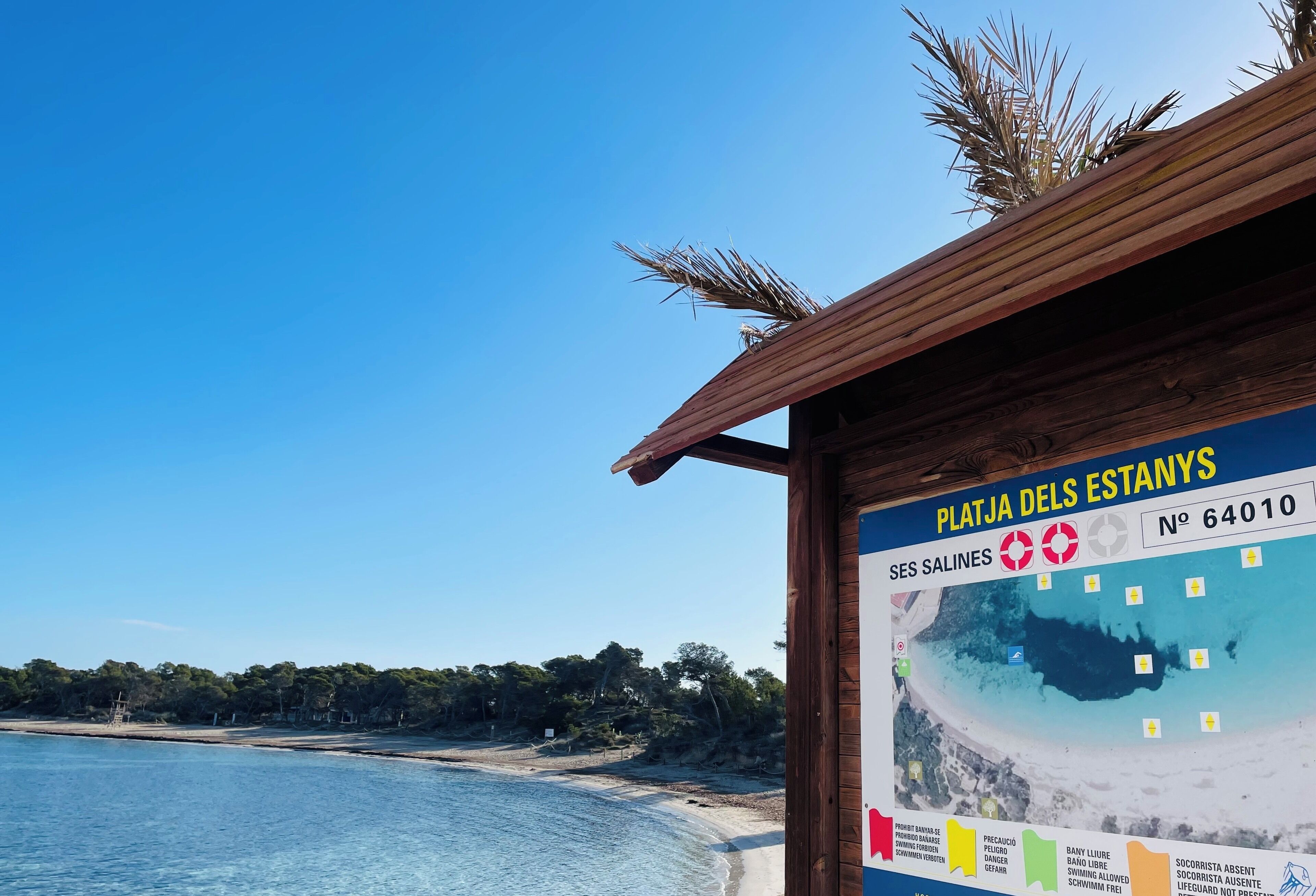 Blick auf einen Strand mit einer Holzkonstruktion, die eine Karte und einen Informationstext zeigt.