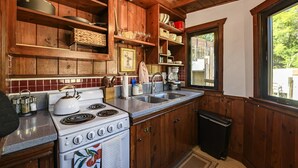 Een keuken met houten kastjes, een fornuis en een spoelbak.