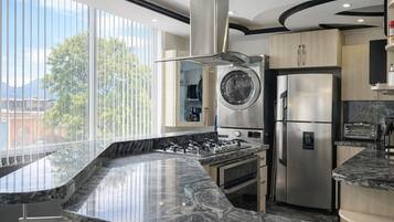 A modern kitchen with a large island, stainless steel appliances, and a view of the outdoors.