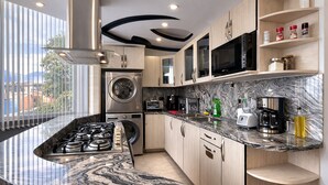A modern kitchen with a curved granite countertop, stainless steel appliances, and a built-in washer and dryer. - Luxury Apartment! Amazing location! Poblado! Lleras! Provenza! Air Conditioning! (Antioquia)