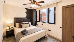 A bedroom with a bed, nightstands, a ceiling fan, a window, and a wardrobe.