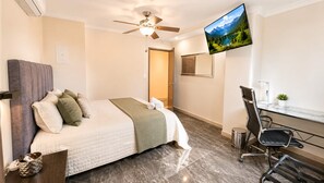 A hotel room with a bed, a desk, a chair, a TV, and a ceiling fan. - Luxury Apartment! Amazing location! Poblado! Lleras! Provenza! Air Conditioning! (Antioquia)