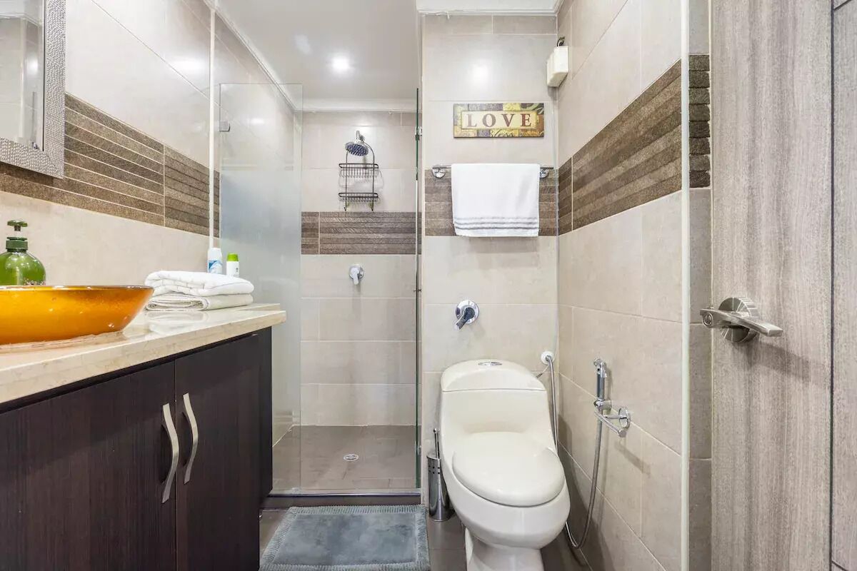 A modern bathroom with a glass shower enclosure, a toilet, and a vanity with a large bowl sink.
