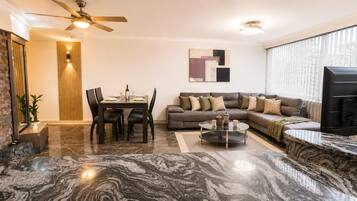 Uma sala de estar moderna com área de jantar, sofás, mesa de centro e televisão.