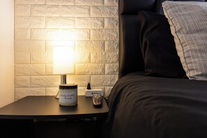 A bedside table with a candle, a remote control, and a power strip. - Luxury Apartment! Amazing location! Poblado! Lleras! Provenza! Air Conditioning! (Antioquia)
