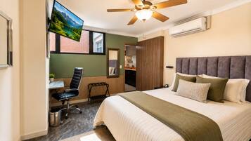 A hotel room with a bed, a desk, a chair, a TV, and a ceiling fan.