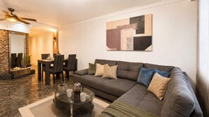 Een moderne woonkamer met een hoekbank, een salontafel en een eethoek met stoelen en een tafel.