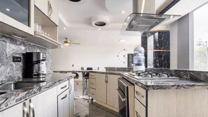 A modern kitchen with a marble countertop, stainless steel appliances, and a large window providing natural light. - Luxury Apartment! Amazing location! Poblado! Lleras! Provenza! Air Conditioning! (Antioquia)