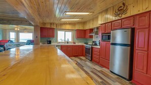 A spacious kitchen with wooden cabinets, a stainless steel refrigerator, and a large island. - Sand Ranch - Epic Ocean View and SPA (Gold Beach)