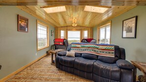 A cozy room with a leather couch, a window with a view, and a ceiling with skylights. - Sand Ranch - Epic Ocean View and SPA (Gold Beach)