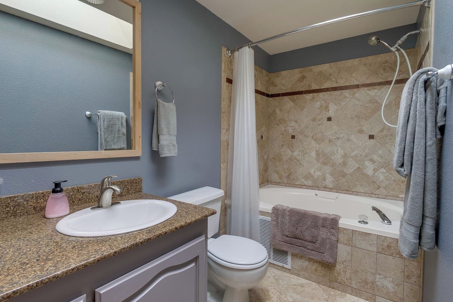 Een badkamer met een wastafel, toilet, douche en bad.