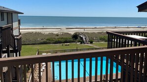 Blick auf einen Strand vom Balkon aus, mit einem Swimmingpool.