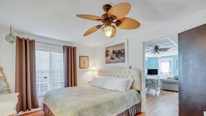 Ein Schlafzimmer mit einem großen Bett, einem Deckenventilator und Blick in einen anderen Raum.