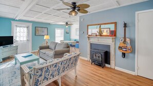Ein Wohnzimmer mit Kamin, Deckenventilator und Gitarre an der Wand.