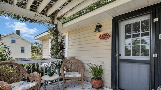 Eine Veranda mit Korbmöbeln, einem Blumentopf und einer Tür mit einer Nummer.