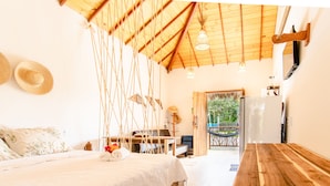 Een knus ingerichte kamer met een bed, een houten tafel, een bureau en een hangmat.