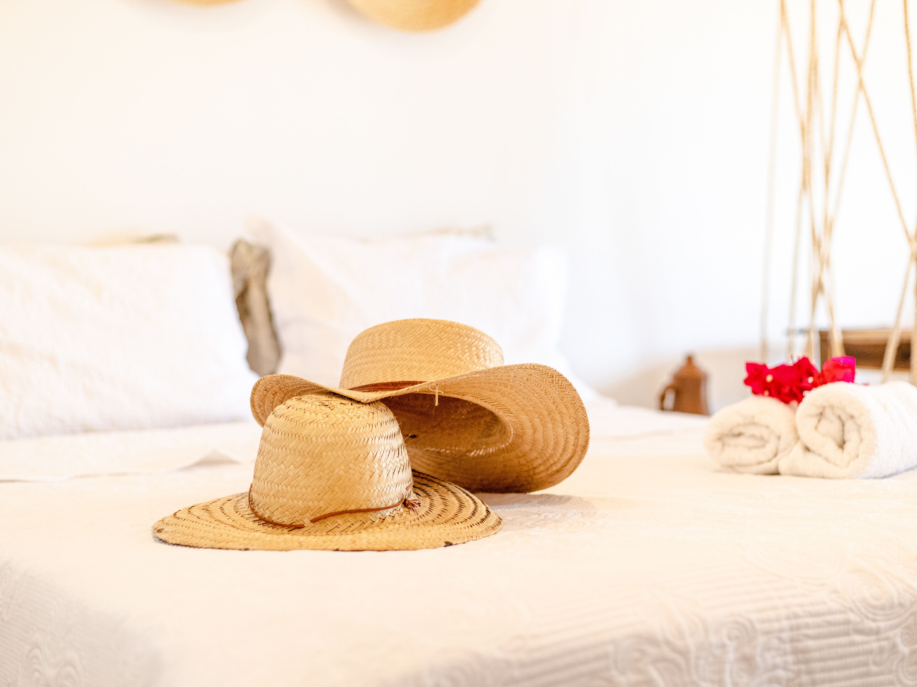 Un lit avec un chapeau de paille et des serviettes enroulées.