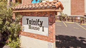 A sign for 'Trinity House I' with a brick facade and a tiled roof.