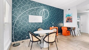 A dining area with a geometric-patterned wall, a round table, and two chairs.