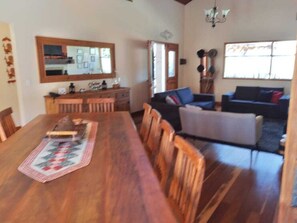 Un comedor con una mesa y sillas de madera, un sofá y un espejo grande sobre la mesa.