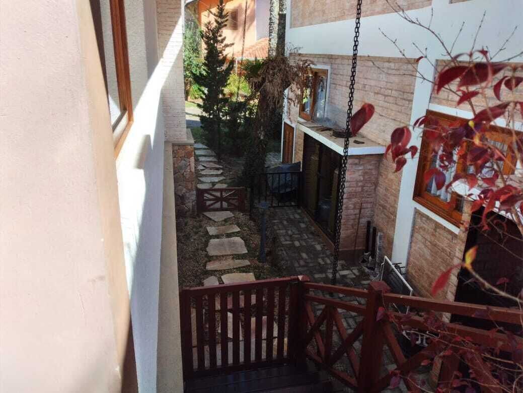 Ein schmaler Außenkorridor mit einem Steinweg, einer hölzernen Bank und einer Schaukel.